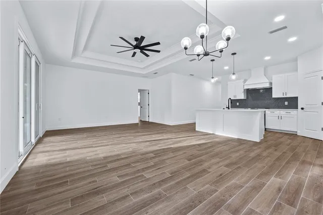 a view of a kitchen with an empty room and wooden floor