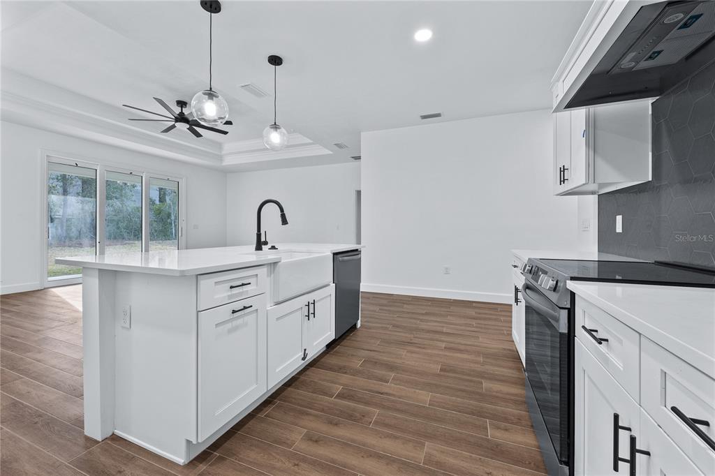 6682 Southwest 10th Lane Gainesville, FL 32607 - Photo 21 of 28 a kitchen with stainless steel appliances granite countertop a sink a stove a refrigerator and white cabinets with wooden floor