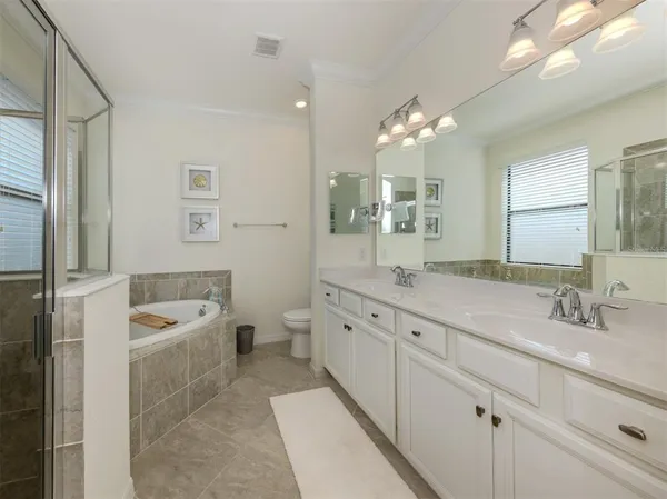 a spacious bathroom with a granite countertop double vanity sink a mirror and a