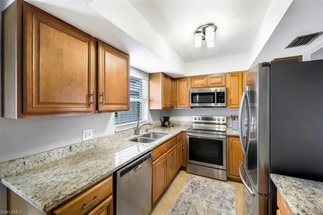 a kitchen with stainless steel appliances granite countertop a stove a sink and a microwave