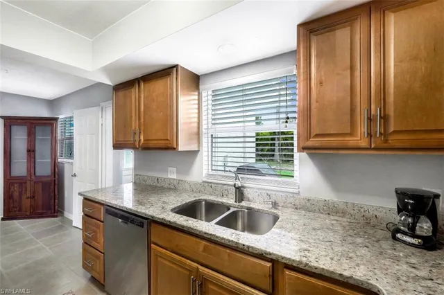 a kitchen with granite countertop a sink and a white wooden cabinets