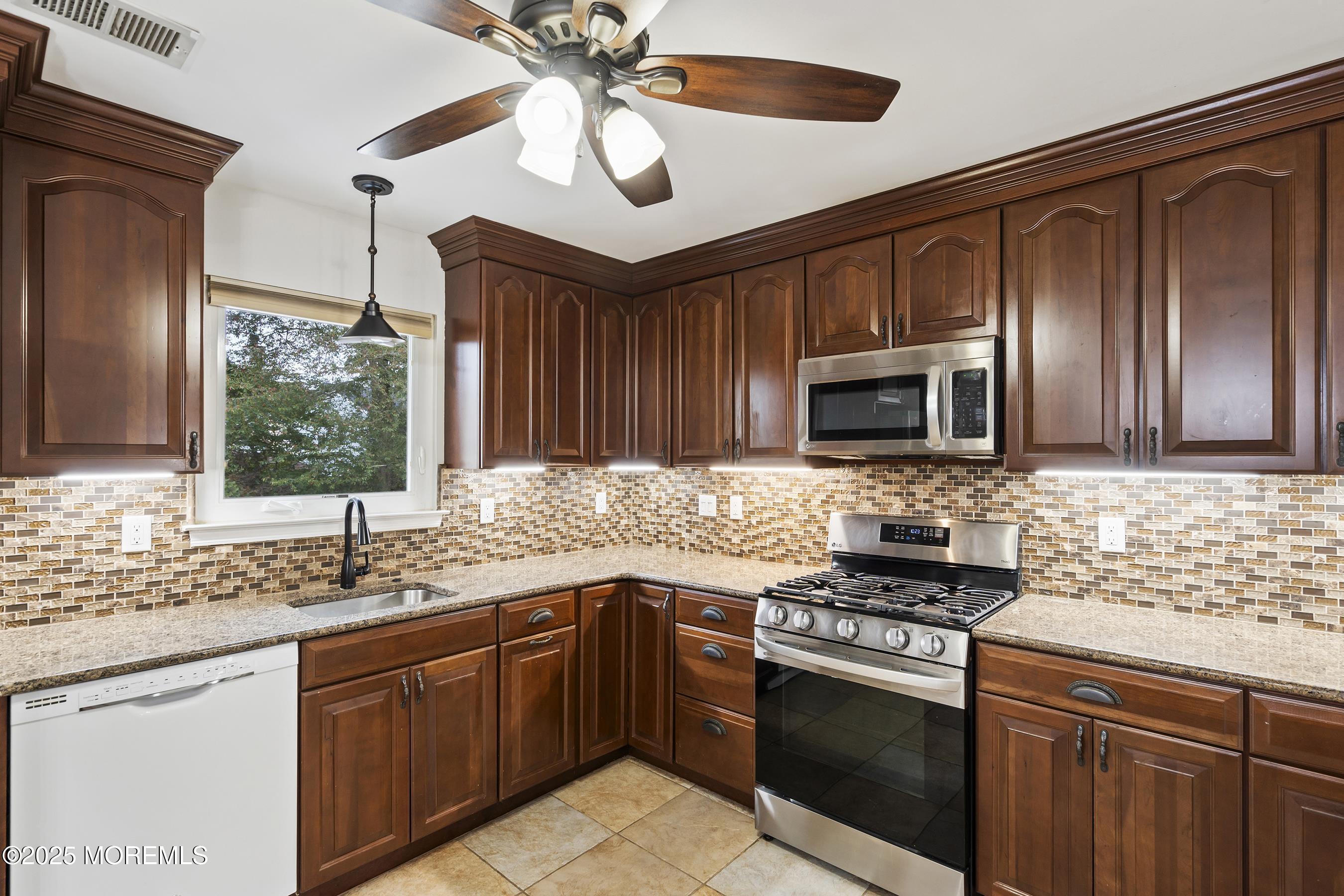 122 Moses Milch Drive Howell, NJ 07731 - Photo 4 of 15 a kitchen with stainless steel appliances granite countertop a sink stove and microwave
