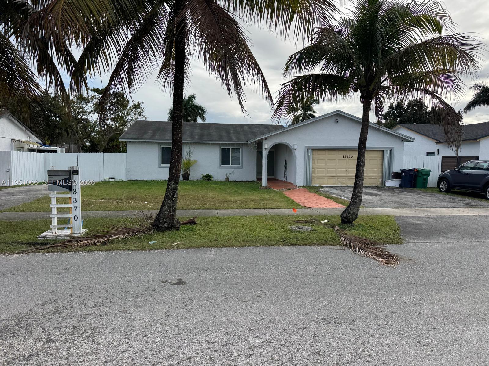 a front view of a house with a yard and palm trees
