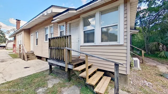a view of a white house with a small yard and furniture