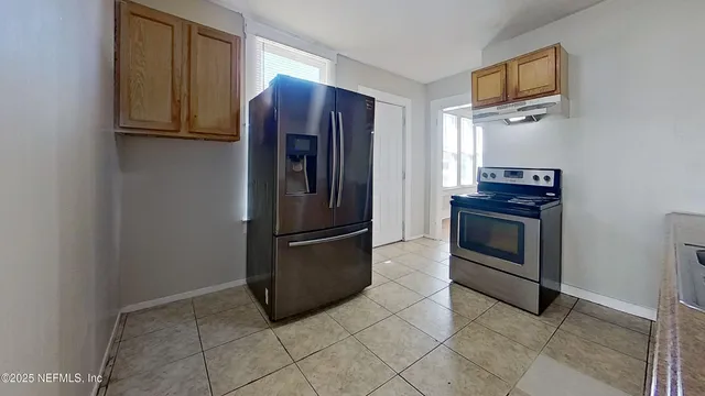 a kitchen with granite countertop a refrigerator and a stove top oven
