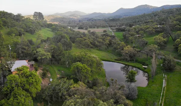 an aerial view of green landscape with trees houses and mountain view