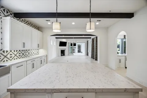 a large white kitchen with a sink and chandelier