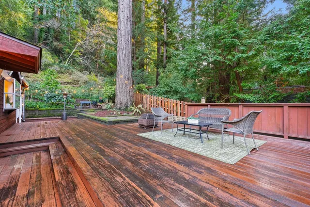 a view of a chairs and table on the wooden roof deck