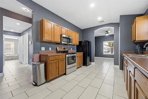 a kitchen with stainless steel appliances granite countertop a stove top oven a sink dishwasher and white cabinets with wooden floor