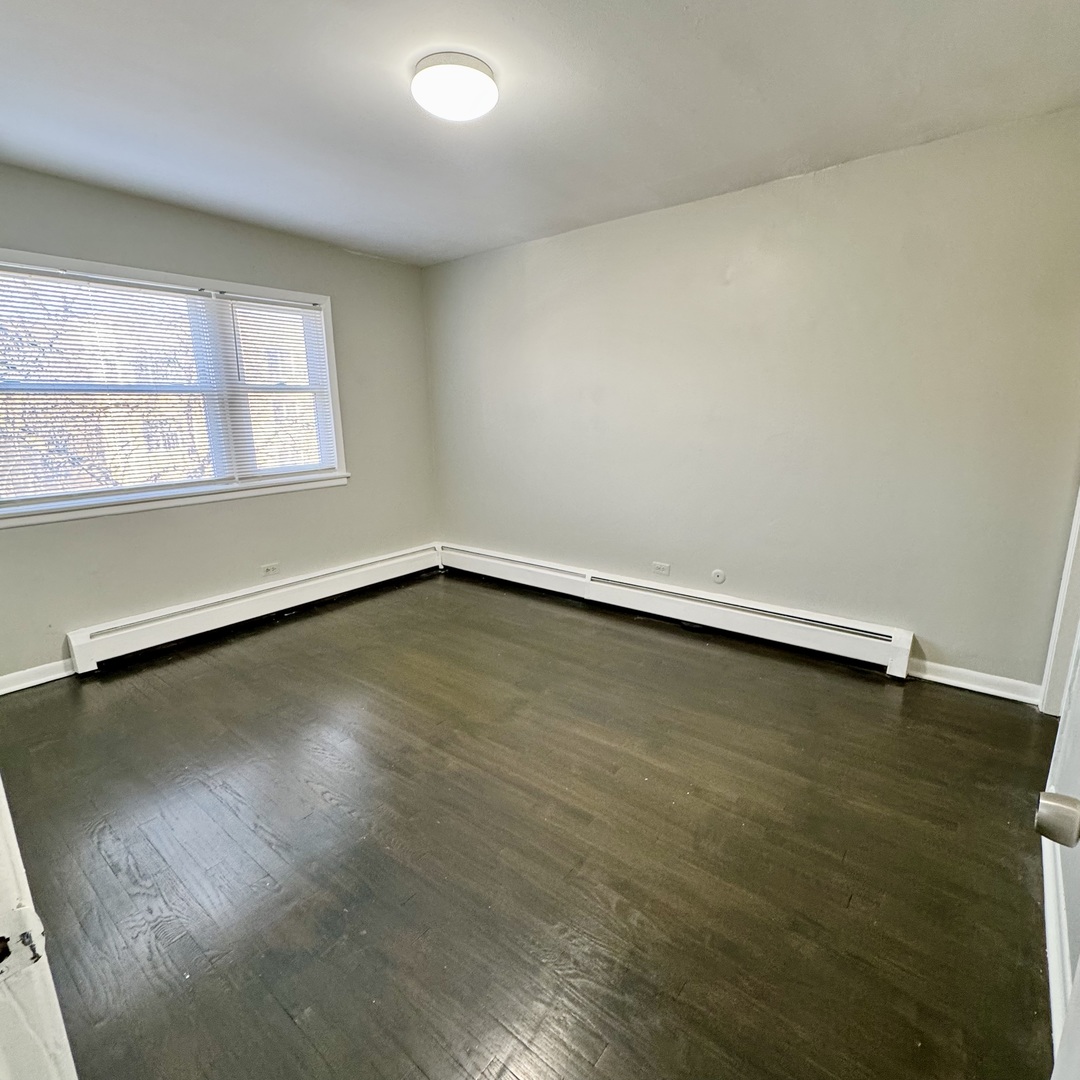 6235 North Mozart Street, Unit 4 Chicago, IL 60659 - Photo 6 of 8 an empty room with wooden floor and windows