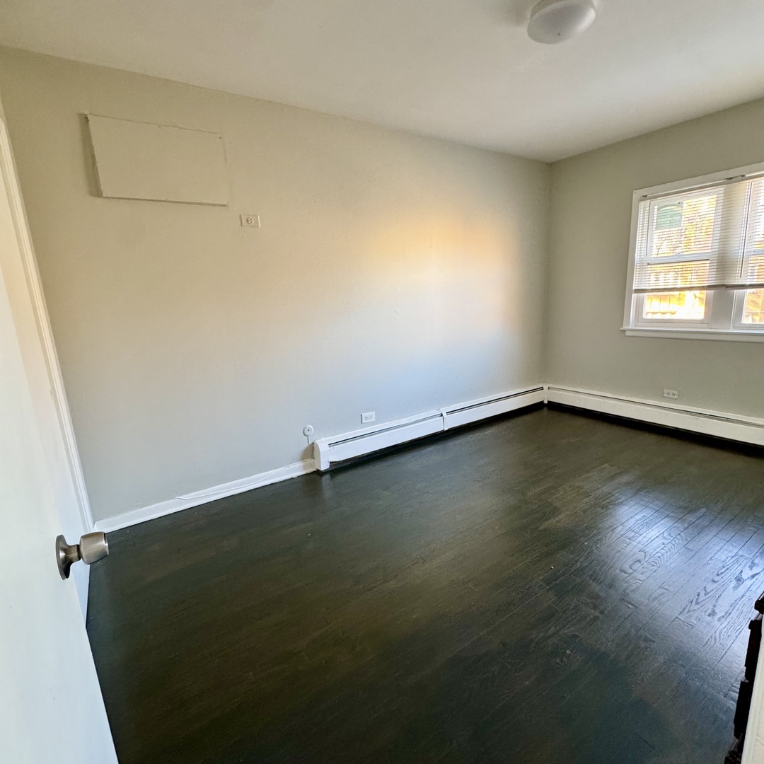 6235 North Mozart Street, Unit 4 Chicago, IL 60659 - Photo 8 of 8 an empty room with wooden floor and windows