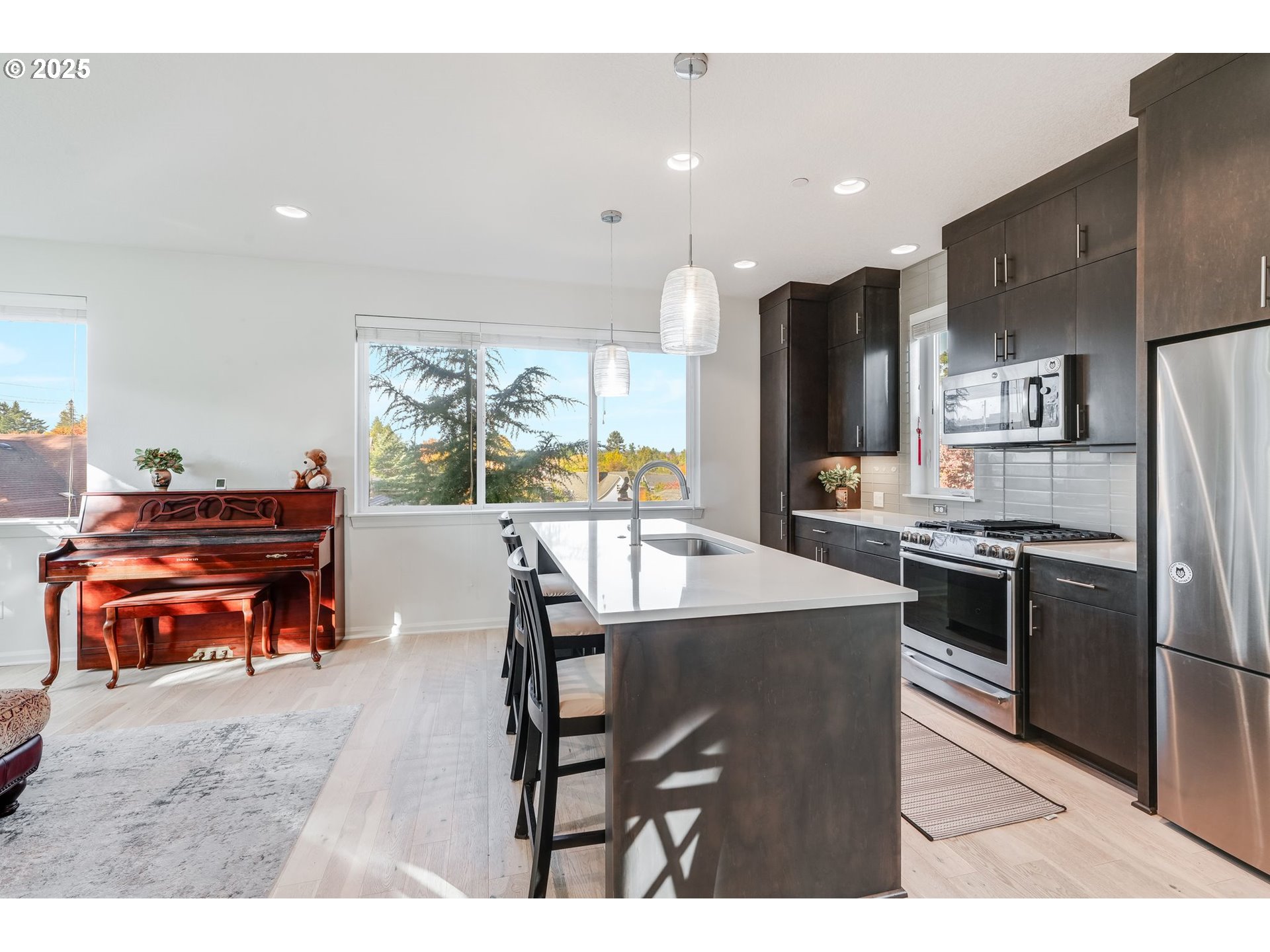 77 Northeast 58th Avenue Portland, OR 97213 - Photo 5 of 36 a kitchen with stainless steel appliances kitchen island granite countertop a refrigerator a stove a sink a dining table and chairs with wooden floor