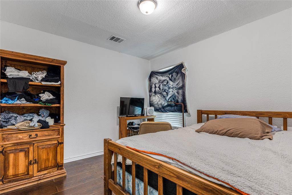548 Elston Drive Dallas, TX 75232 - Photo 10 of 18 Bedroom featuring dark wood finished floors, a textured ceiling, and a textured wall