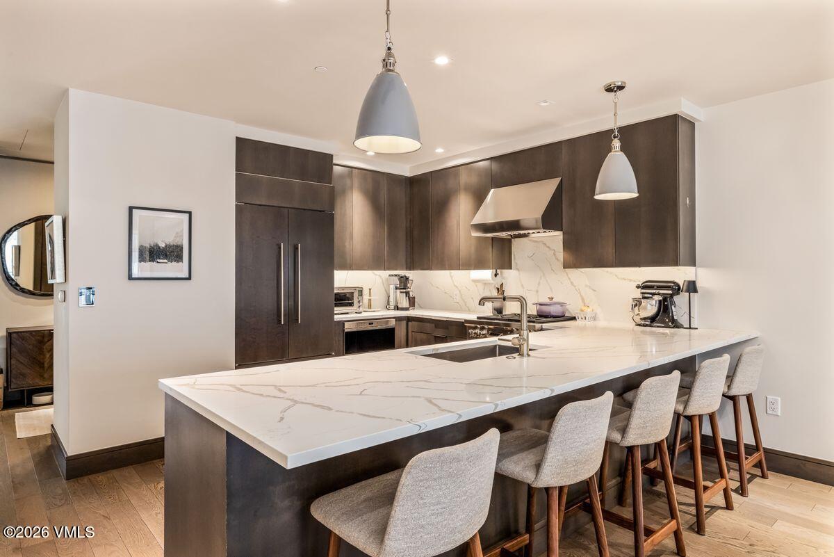 430 South Frontage Road East, Unit RU303 Vail, CO 81657 - Photo 4 of 39 a kitchen with stainless steel appliances kitchen island a table chairs sink and cabinets