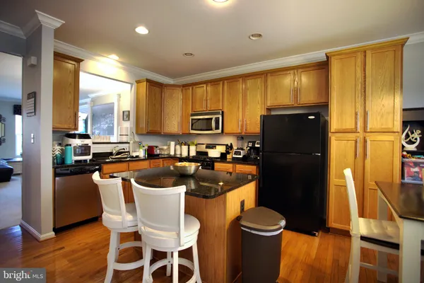 a kitchen with a refrigerator a stove a sink dishwasher and a dining table with wooden floor