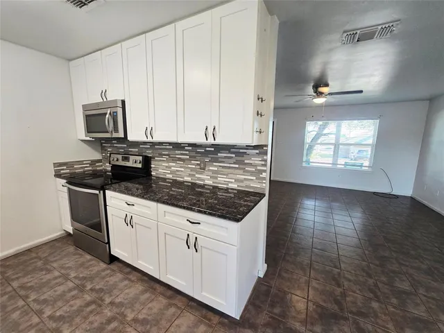 a kitchen with stainless steel appliances granite countertop a stove a sink and a microwave