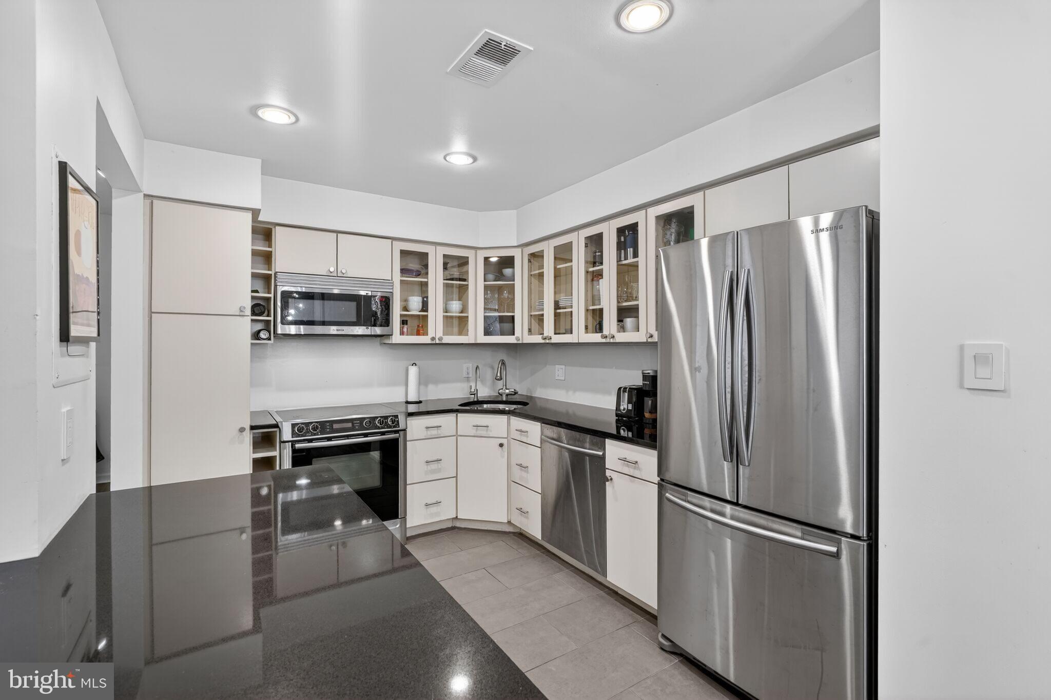 1045 31st Street Northwest, Unit 21 Washington, DC 20007 - Photo 6 of 35 a kitchen with stainless steel appliances granite countertop a refrigerator and a stove top oven