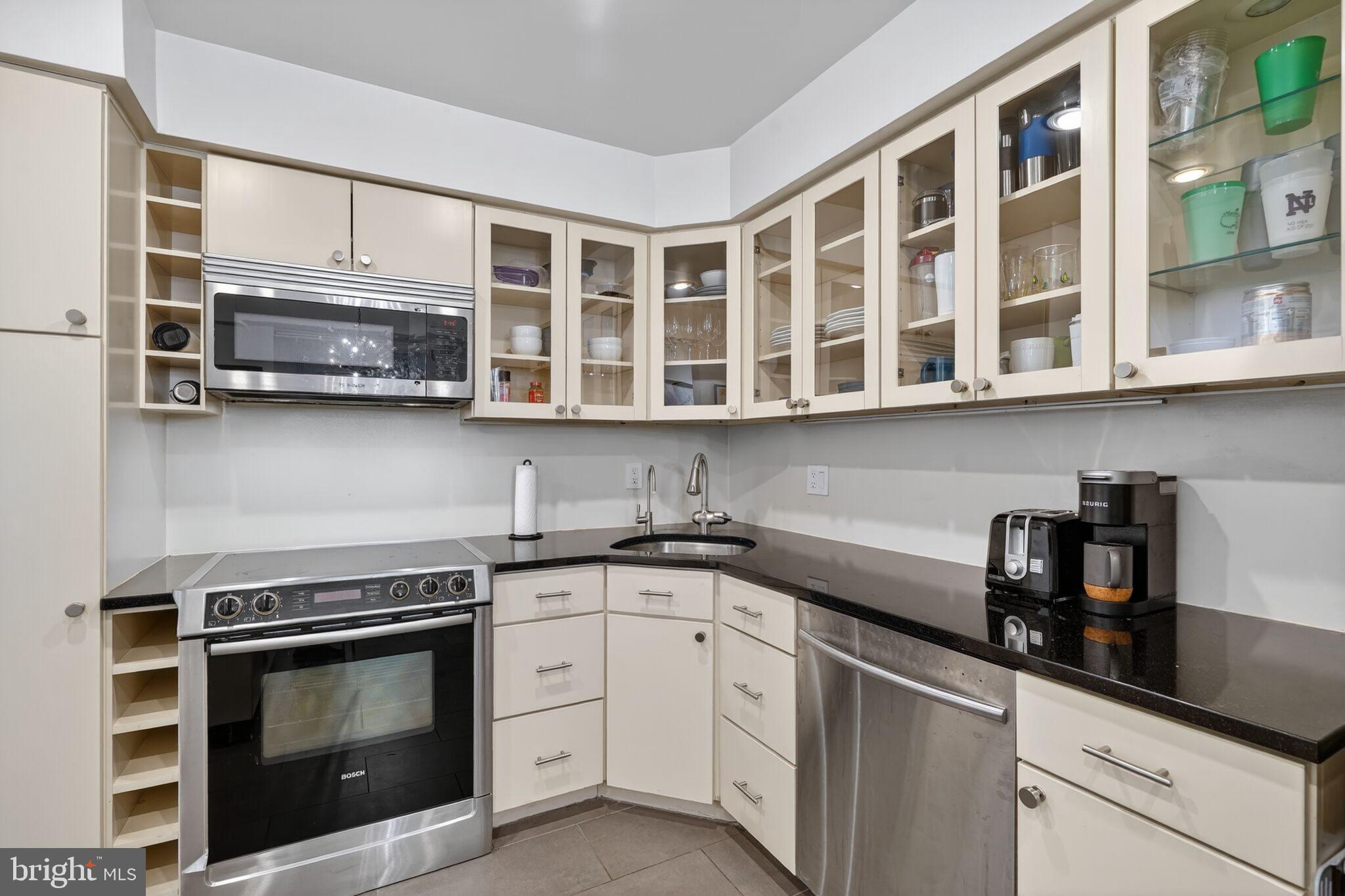1045 31st Street Northwest, Unit 21 Washington, DC 20007 - Photo 7 of 35 a kitchen with stainless steel appliances granite countertop a stove microwave and cabinets