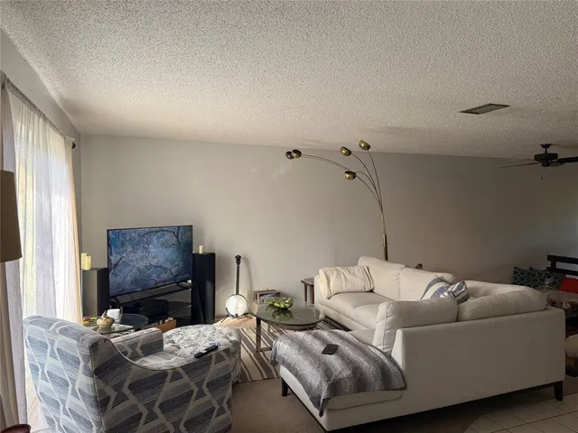 a living room with furniture a flat screen tv and a window