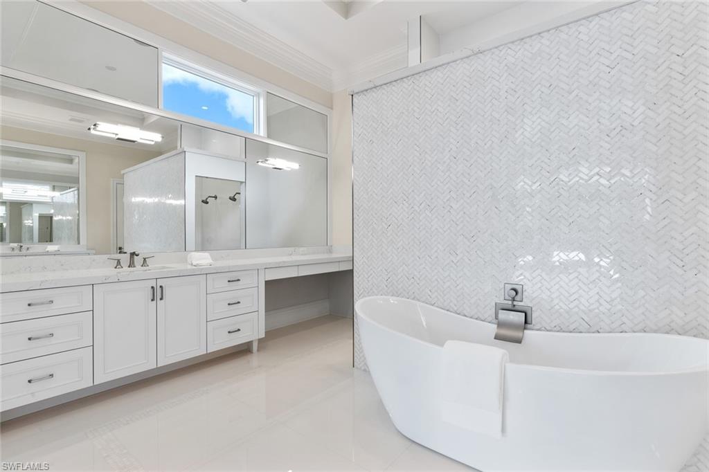 1670 Crayton Road Naples, FL 34102 - Photo 12 of 26 a bathroom with a bathtub a double vanity sink and mirrors