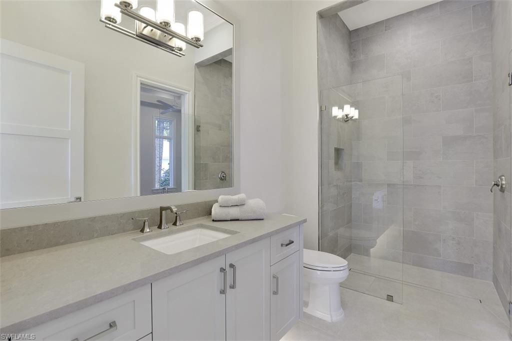 1670 Crayton Road Naples, FL 34102 - Photo 23 of 26 a bathroom with a toilet a sink a mirror and a shower
