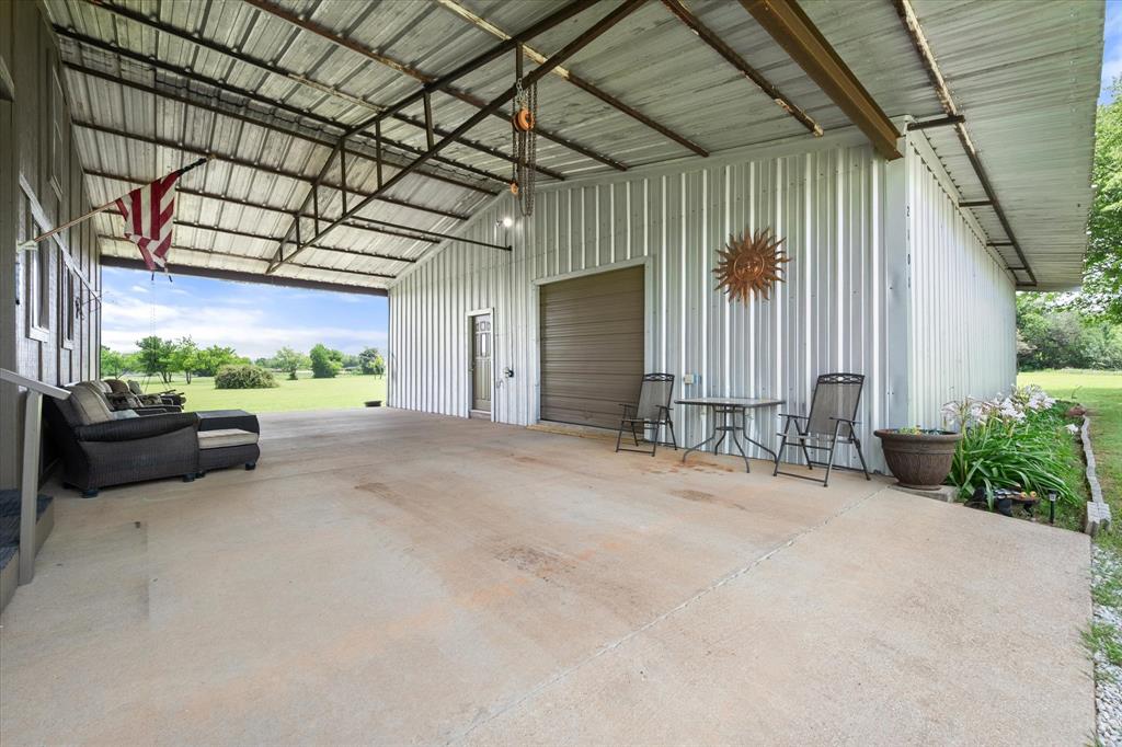 2101 Ridge View Drive Cleburne, TX 76033 - Photo 25 of 31 Expansive covered concrete patio featuring a corrugated metal roof and exposed support beams