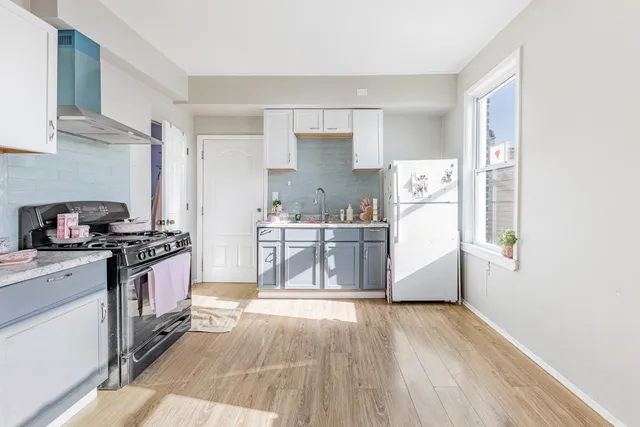 a kitchen with stainless steel appliances a stove a sink and white cabinets with wooden floor