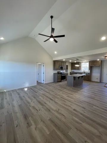 an empty room with wooden floor fan and windows