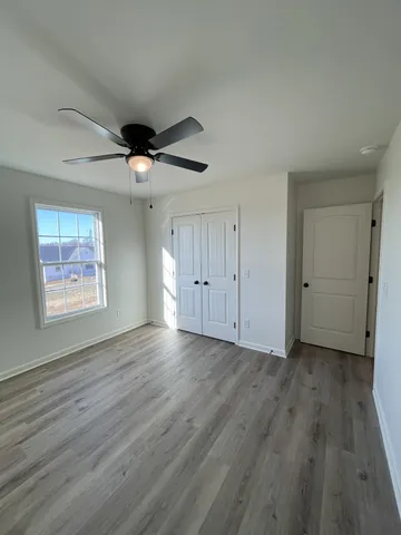 an empty room with wooden floor fan and windows