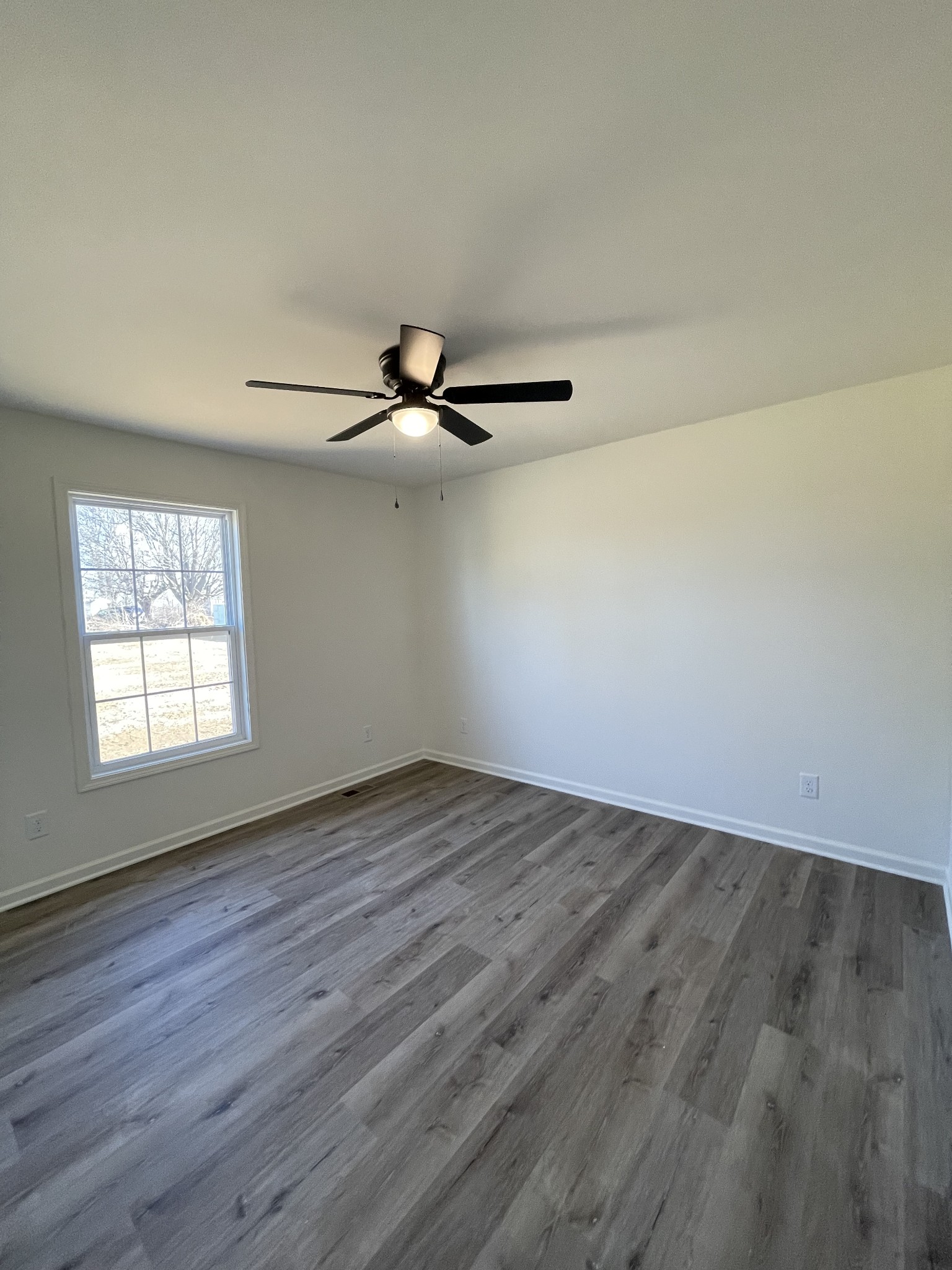 586 Pleasant Hill Road Lafayette, TN 37083 - Photo 26 of 38 an empty room with wooden floor fan and windows