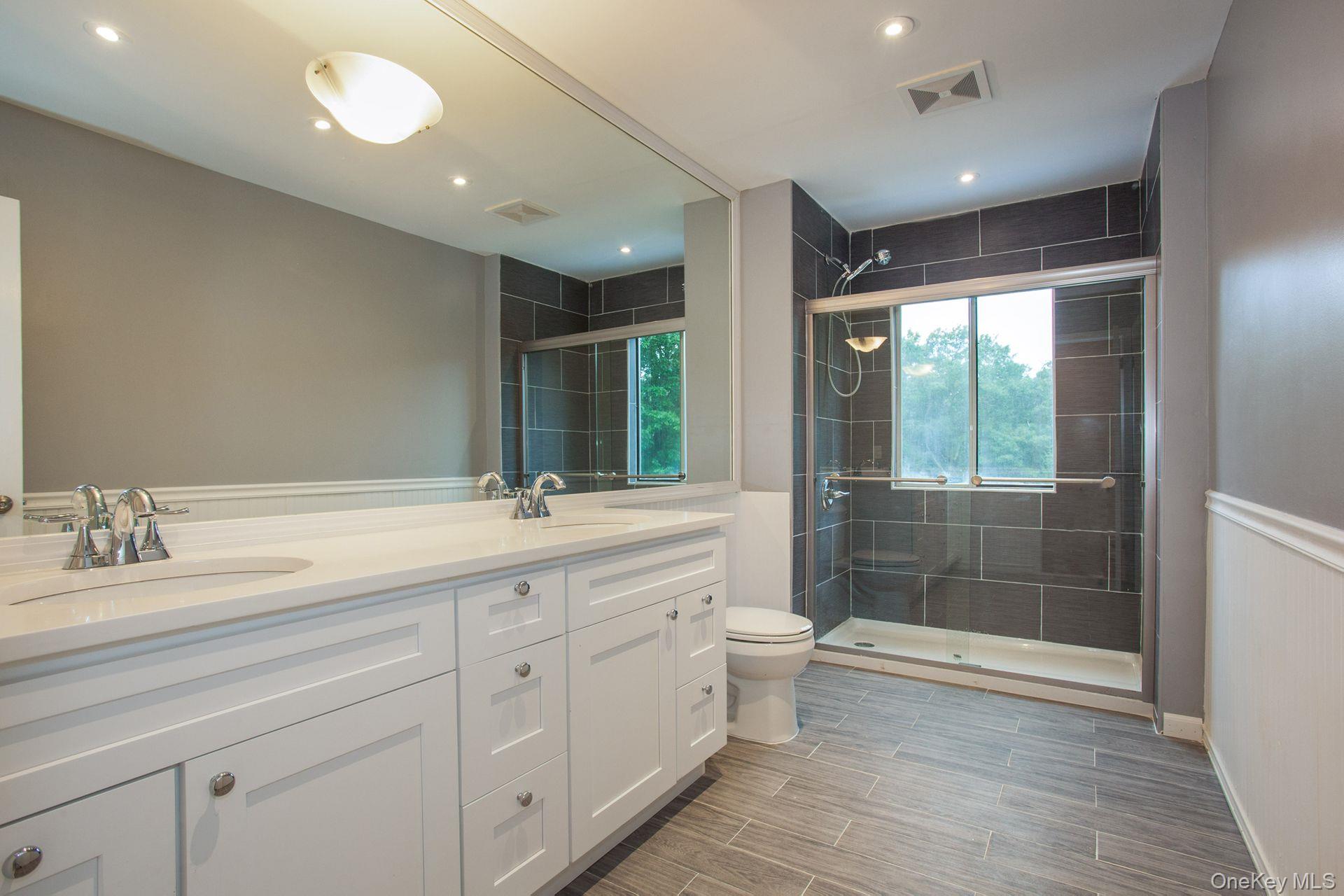 12 North Ridge Road Setauket, NY 11733 - Photo 19 of 34 a bathroom with a double vanity sink a toilet and shower