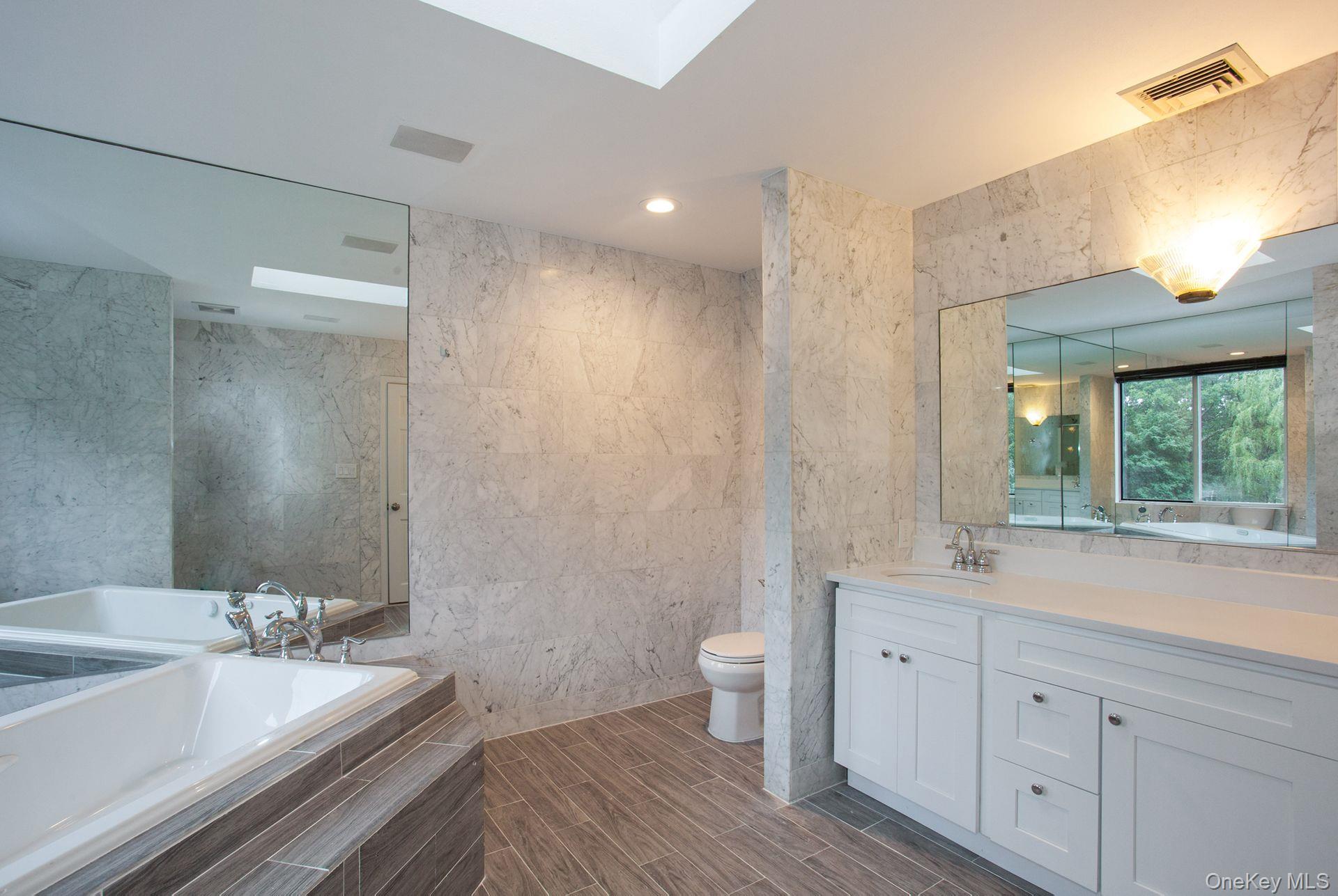 12 North Ridge Road Setauket, NY 11733 - Photo 22 of 34 a spacious bathroom with a double vanity sink toilet mirror and bathtub