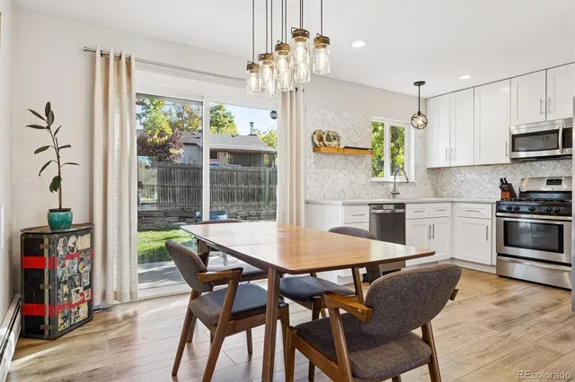 a kitchen with stainless steel appliances granite countertop a table chairs and a refrigerator
