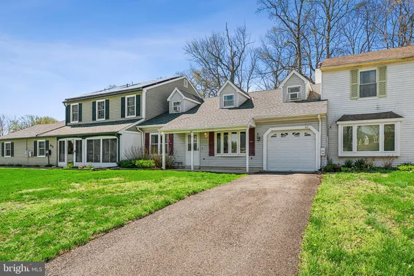 a front view of a house with a garden and trees