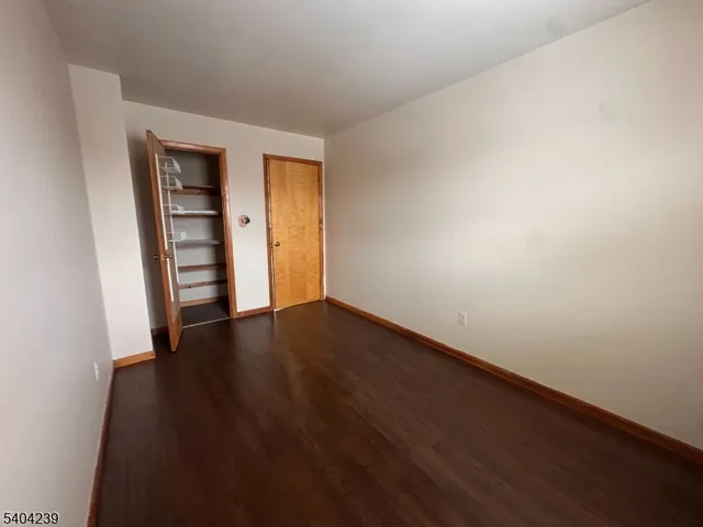 a view of an empty room with wooden floor and closet