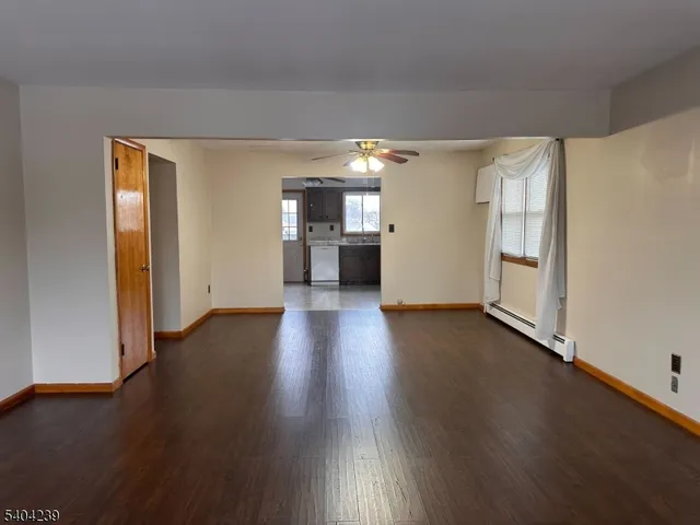 a view of a big room with wooden floor and a kitchen
