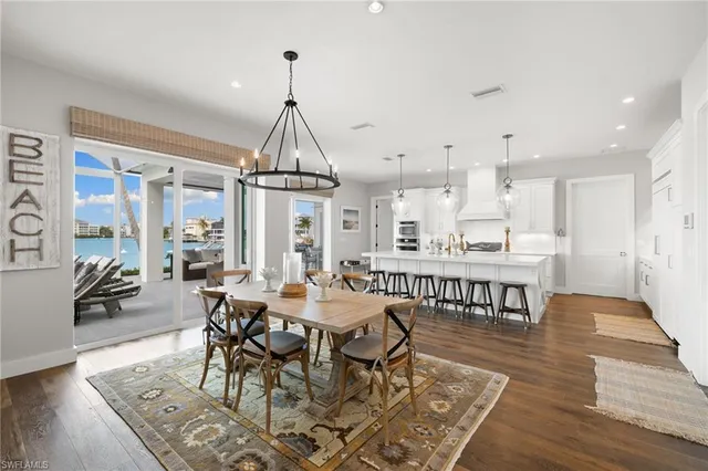 a view of a a dining room and livingroom with furniture wooden floor a chandelier