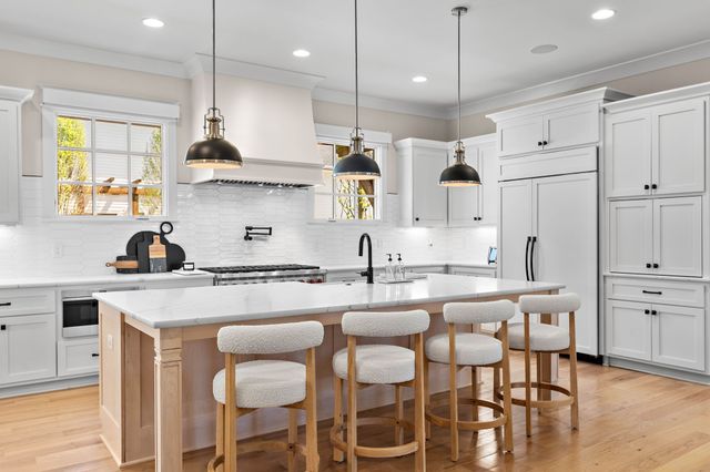 a kitchen with stainless steel appliances a stove a sink and a white wooden cabinets