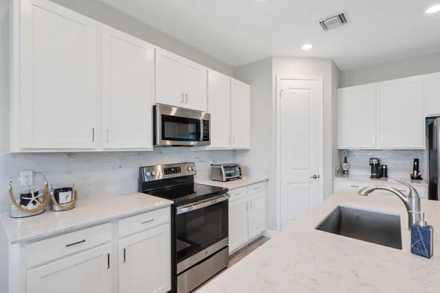 a kitchen with granite countertop a sink a stove and cabinets