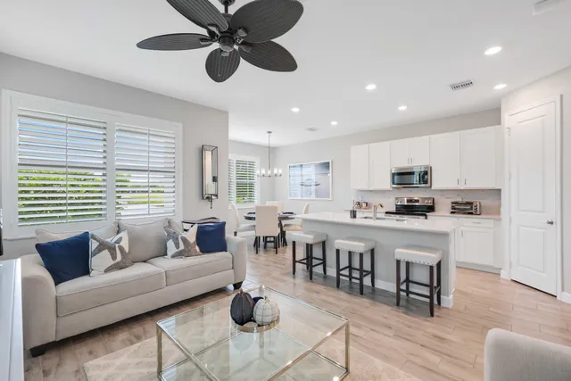 a living room with stainless steel appliances furniture a dining table and kitchen view