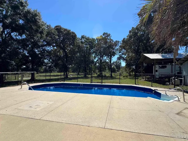 a view of swimming pool with seating area and trees in the background