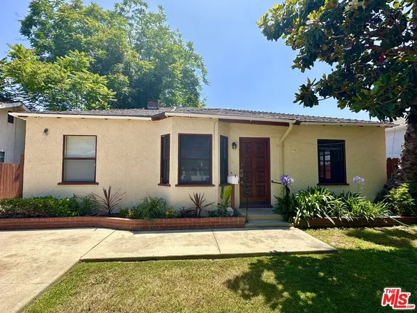 a view of a house with a yard and a large tree