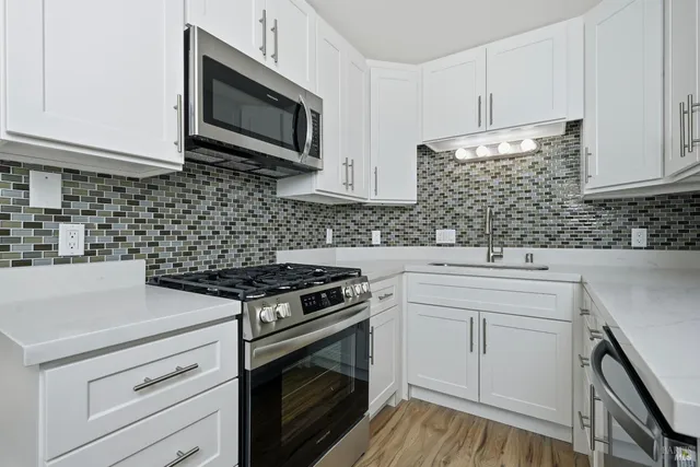 a kitchen with granite countertop cabinets stainless steel appliances and wooden floor
