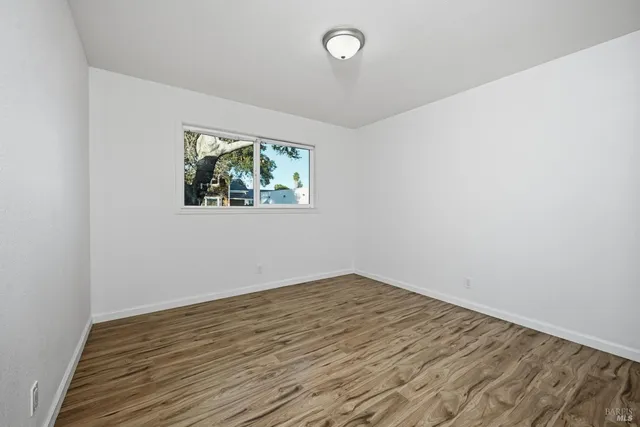an empty room with wooden floor and window