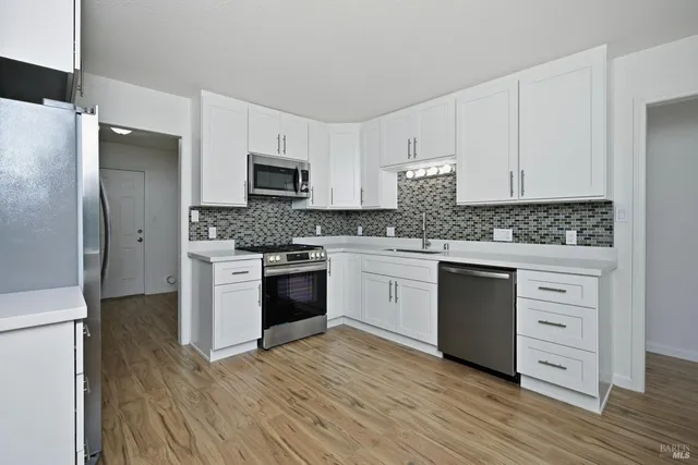 a kitchen with granite countertop a sink cabinets and stainless steel appliances