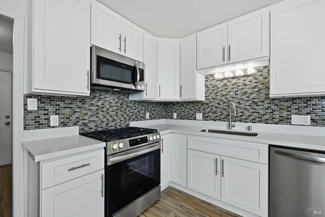 a kitchen with white cabinets stainless steel appliances and sink