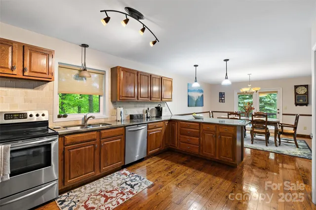 a kitchen with stainless steel appliances granite countertop wooden cabinets a stove a sink and dishwasher a oven with wooden floor