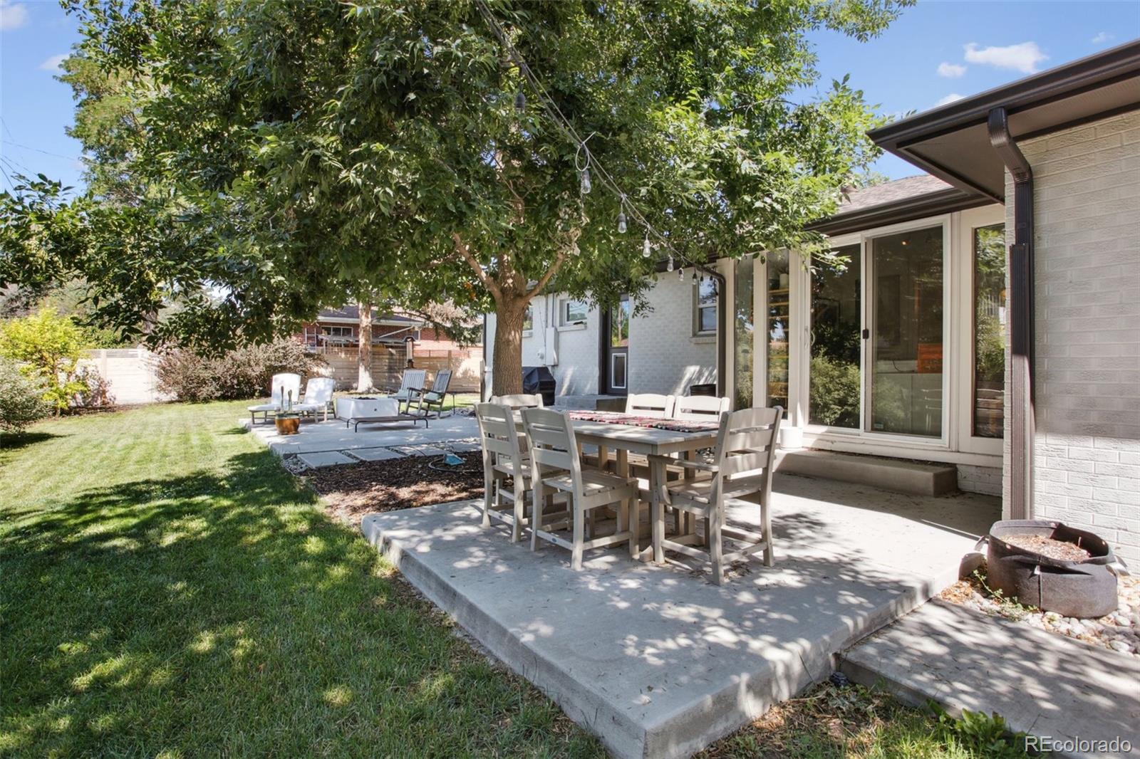 7130 West 30th Avenue Wheat Ridge, CO 80033 - Photo 35 of 37 a view of a patio with table and chairs next to a yard