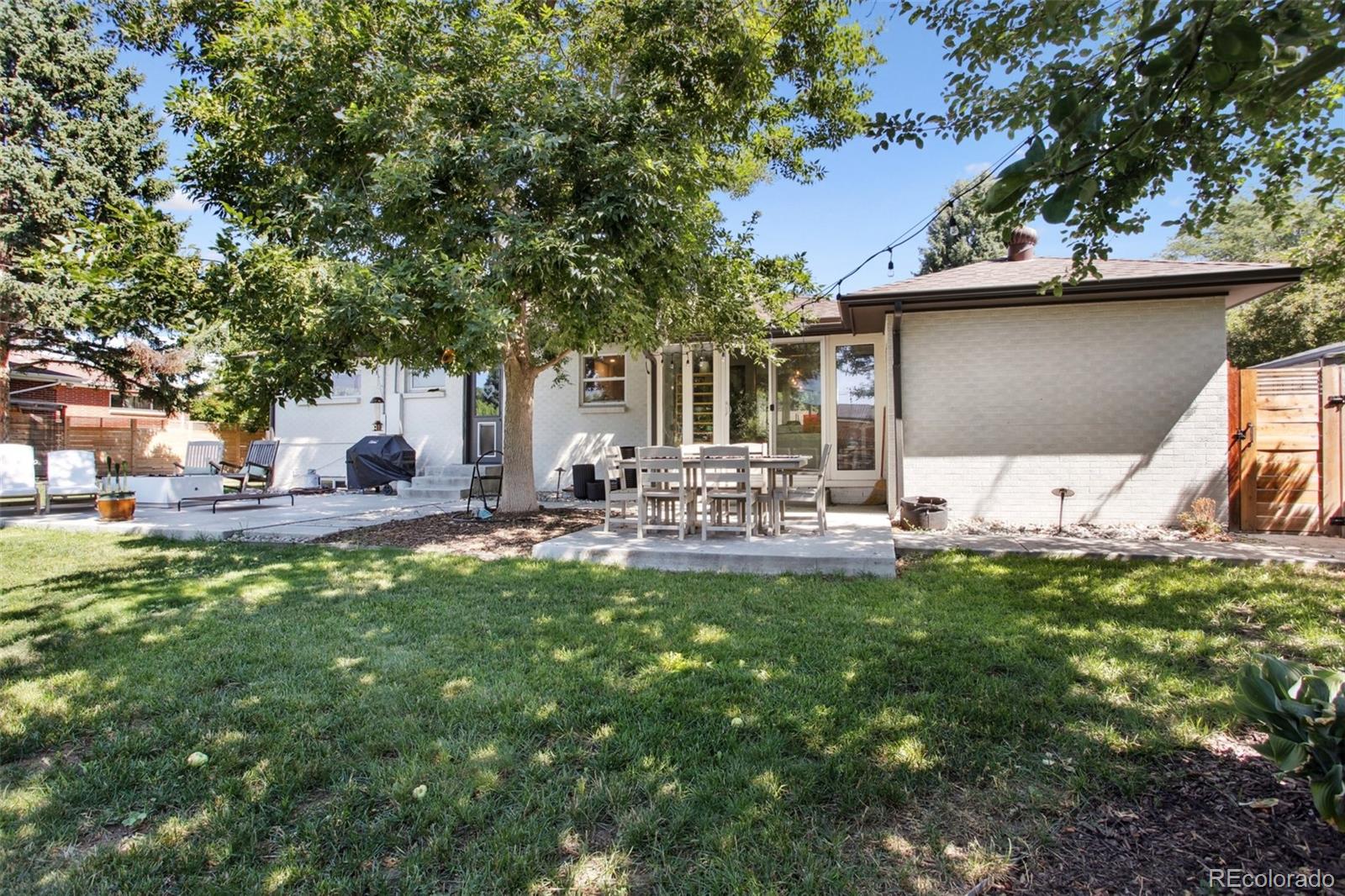 7130 West 30th Avenue Wheat Ridge, CO 80033 - Photo 36 of 37 a view of a patio with table and chairs potted plants and large tree