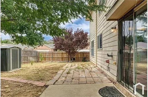 a view of a house with a large tree and wooden fence